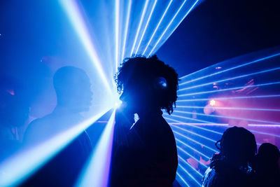 Happy black couple dancing against colorful neon illumination during party in nightclub