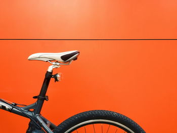 Bicycle parked against orange wall