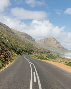 Road by mountains against sky