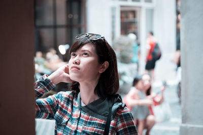 Young woman looking up while standing in city