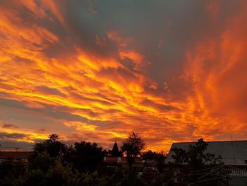 Silhouette houses against dramatic sky during sunset