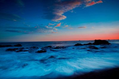 Scenic view of sea against dramatic sky during sunset