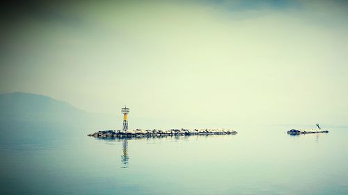 Lighthouse on rocks in lake against sky