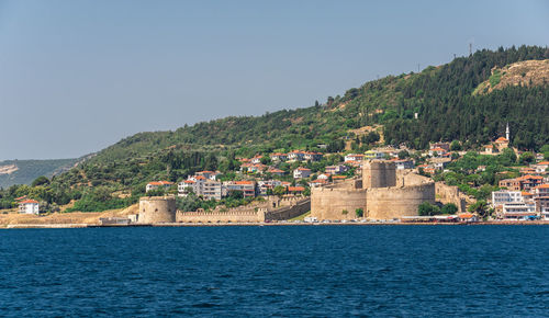 Buildings by sea against clear sky