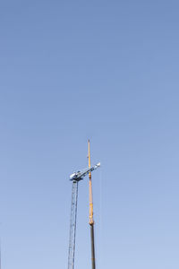 Low angle view of crane against clear blue sky