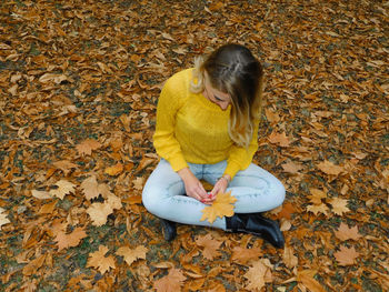 High angle view of woman sitting on autumn leaves
