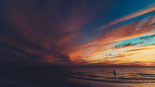 Scenic view of sea against dramatic sky during sunset