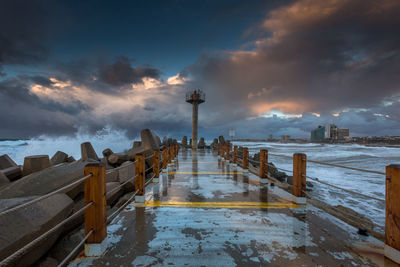 Pier on sea against cloudy sky