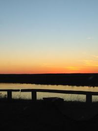 Silhouette bridge over river against sky during sunset