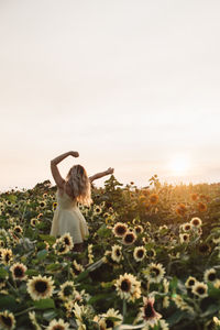 Rear view of woman on field against sky during sunset