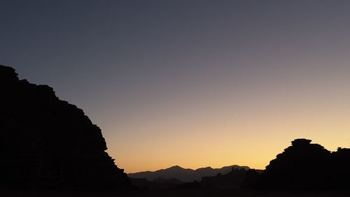 Silhouette mountains against clear sky during sunset