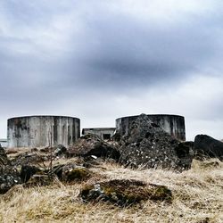 Old ruin on field against cloudy sky