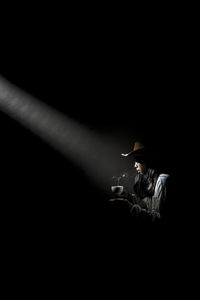 Midsection of man holding cigarette against black background