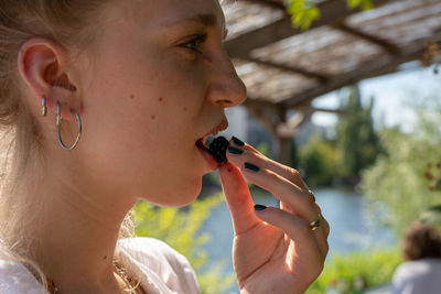 Midsection of woman eating blackberry 