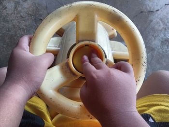 Small child's hand pressing the horn of a yellow toy car