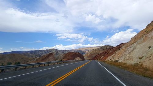 Empty road by mountains against sky