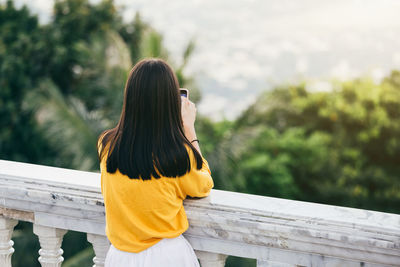 Rear view of woman standing on railing