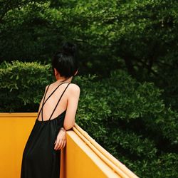 Rear view of woman standing against trees