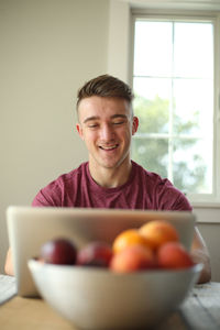 Portrait of young man with fruits in bowl at home