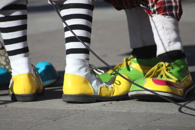 Low section of people wearing clown shoes while standing on street