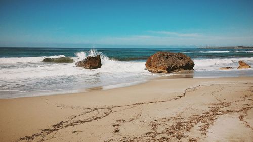 Scenic view of beach against clear blue sky