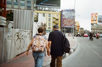 Rear view of friends walking on street in city