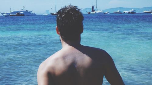 Rear view of shirtless man standing on sea against sky