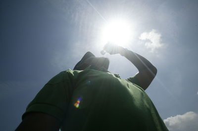 Midsection of man with sun shining in sky