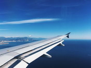 Airplane flying over sea against blue sky