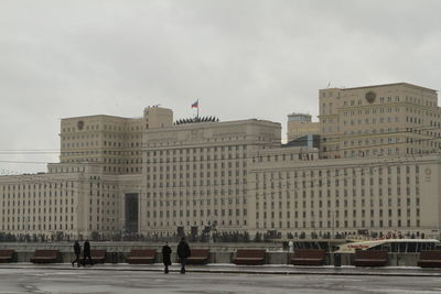 People on street amidst buildings in city against sky