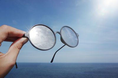 Midsection of person holding sea against sky