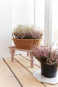 Indoor dry purple heather flowers in a wicker basket on the windowsill of the house