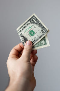 Cropped hand holding paper currency against gray background