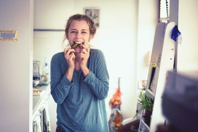 Portrait of happy young woman eating food at home