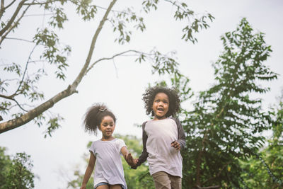 Siblings walking against trees