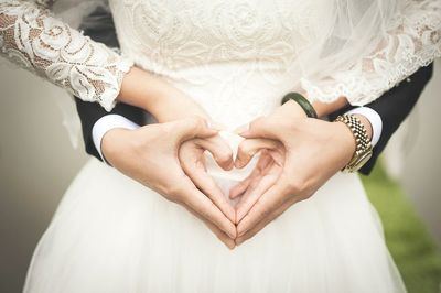 Midsection of woman holding heart shape on white