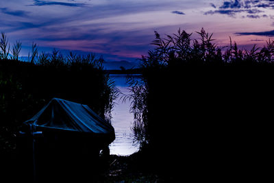 Silhouette trees by lake against sky during sunset