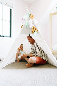 Portrait of a father and daughter reading together in a play tipi