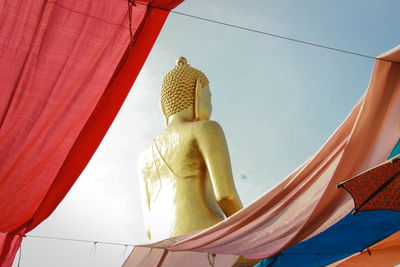 Low angle view of buddha statue against sky