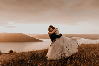 Rear view of woman standing on field against sky