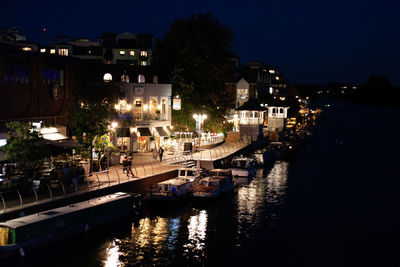 Canal amidst illuminated buildings in city at night