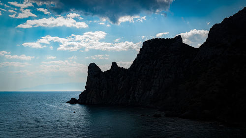 Scenic view of sea by cliff against sky