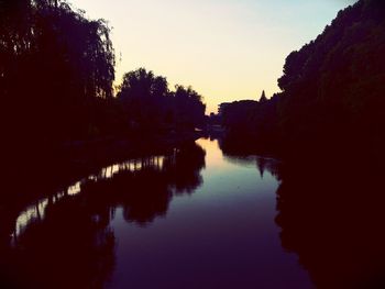 Reflection of silhouette trees in lake against sky