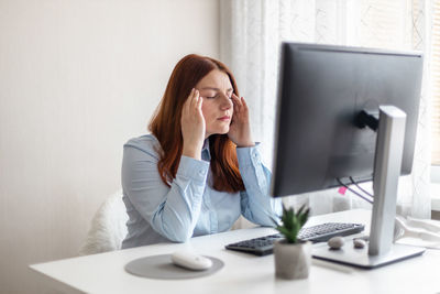 Young woman using mobile phone while sitting at home