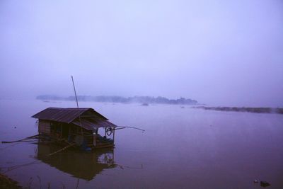 House on lake by building against sky