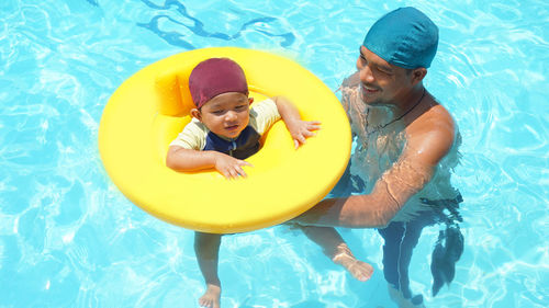 High angle view of father and son swimming in pool