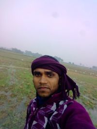 Portrait of man standing on field against sky