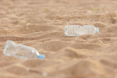 Close-up of water bottle on sand at beach