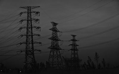 Low angle view of electricity pylon against sky at sunset