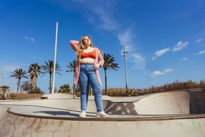 Full length of young woman standing against sky